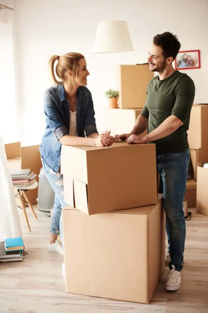Relocation specialists having a conversation leaning on stacked up boxes