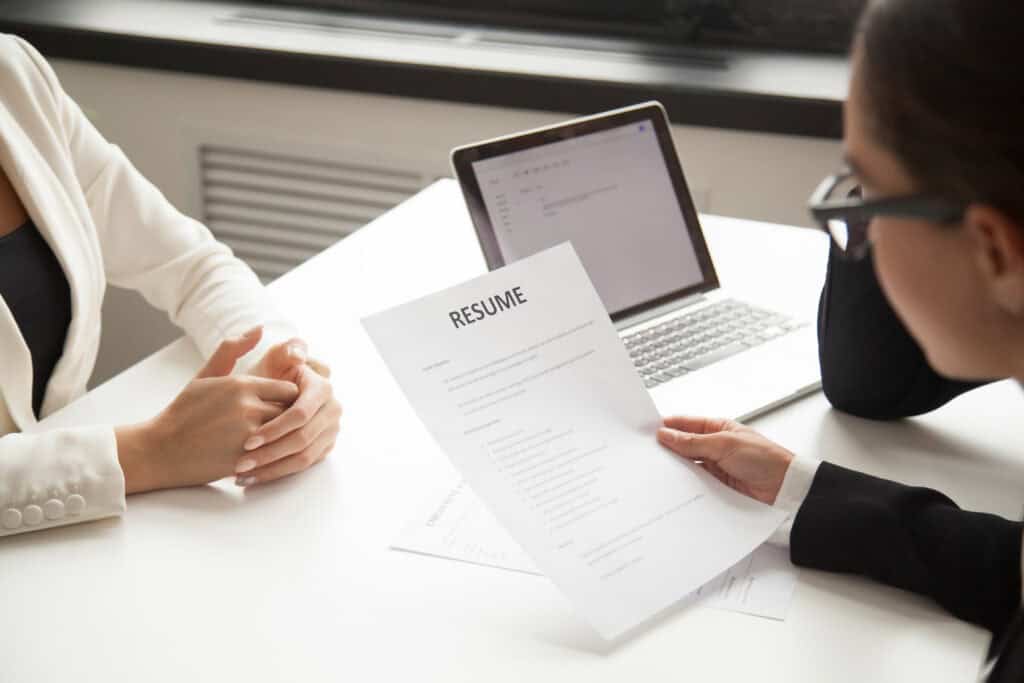 HR manager reading applicant resume while employee waits for questions