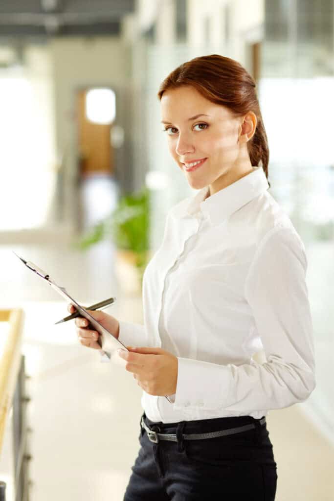 Young businesswoman with document and pen in her hands looking at camera and smiling