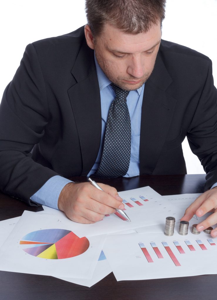 Bussinesman in suite and tie analyzing graphs at the office on white background